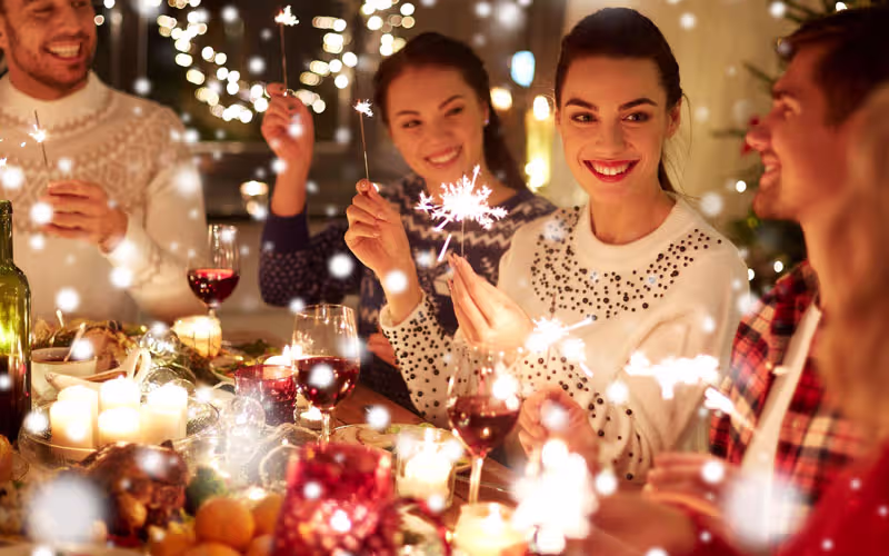Foto Mitarbeiter beim Essen mit Wunderkerzen zur Weihnachtsfeier